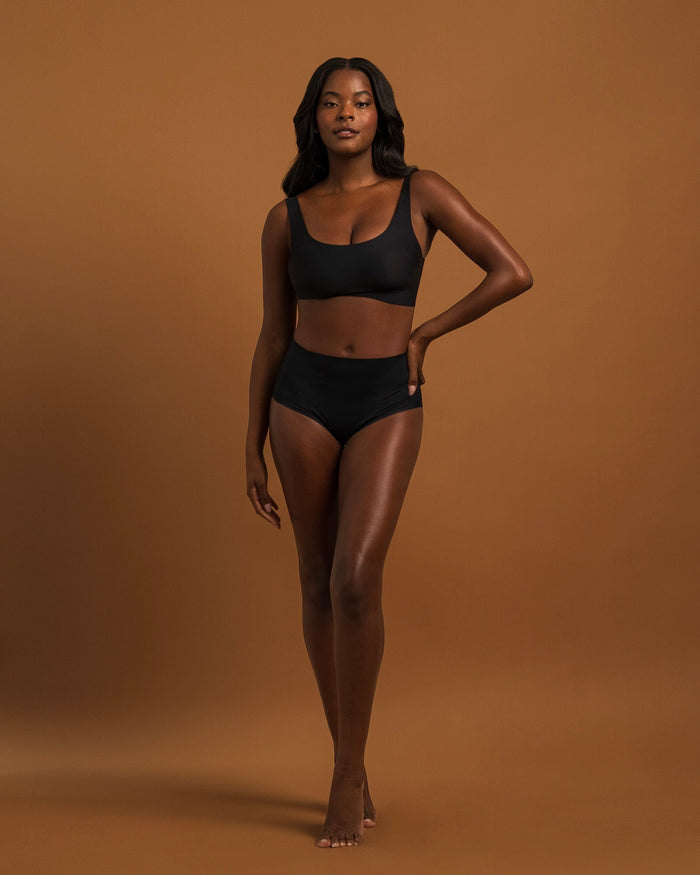 Woman wearing the Seamless Shaping Brief in Black, full-length front view, worn with a matching bra