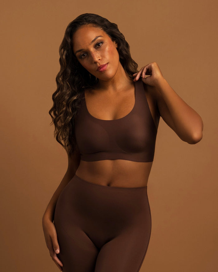 Woman wearing the Seamless Wireless Full Coverage Bra in Hazelnut, three-quarter view with one arm raised