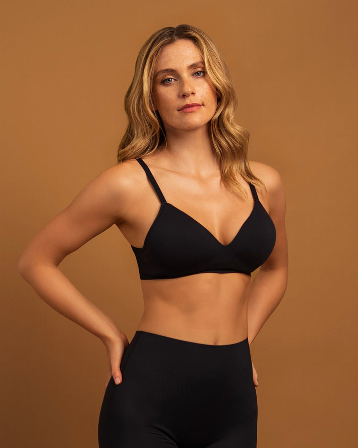 Woman wearing the Seamless Wireless T-Shirt Bra in Black, front view, hand on hip