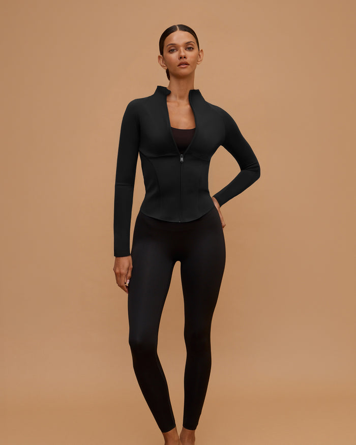 Woman wearing the Sculpt & Move Raglan Jacket in Black, full-length front view, hand on hip